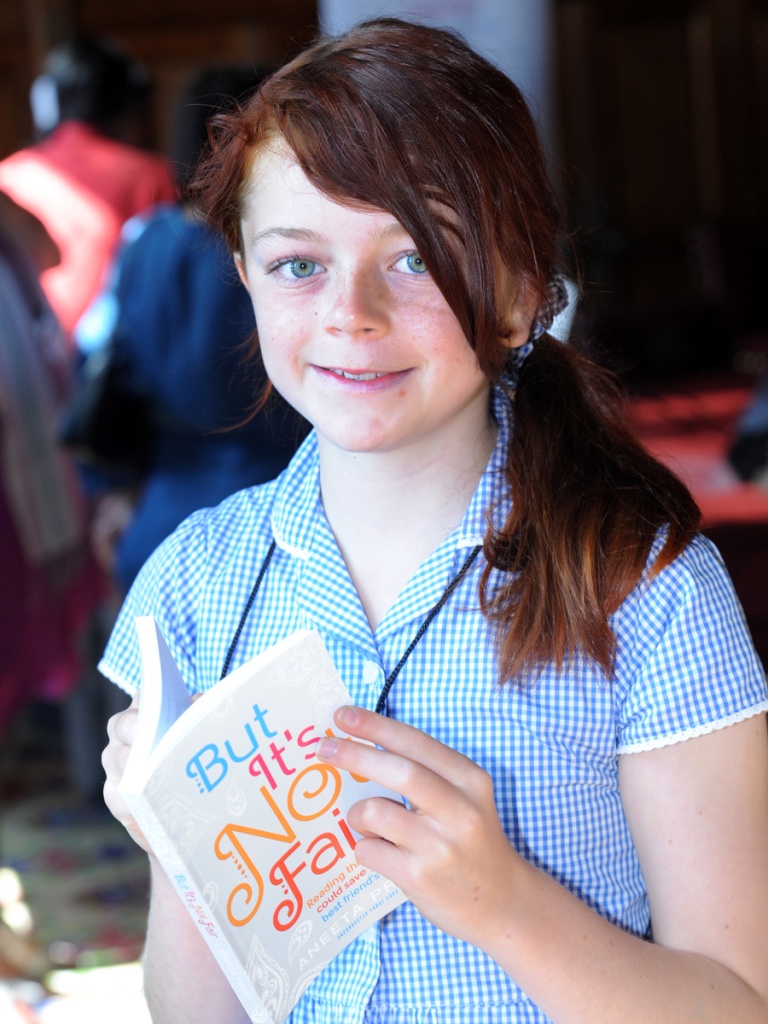 A young reader holding the original edition of But It's Not Fair