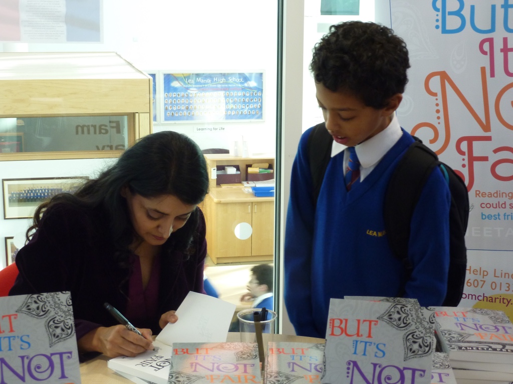 Aneeta Prem signing But It's Not Fair at a school event